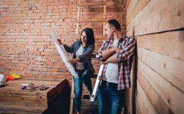 Couple looks at blueprints before starting a DIY home improvement project - cheap home insurance.