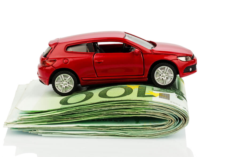 Red toy car on top of a bunch of hundred dollar bills - cheap SR22 insurance.