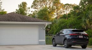 Car parked in front of wide garage double door on concrete driveway of new modern american house - Acceptance, cheap business insurance