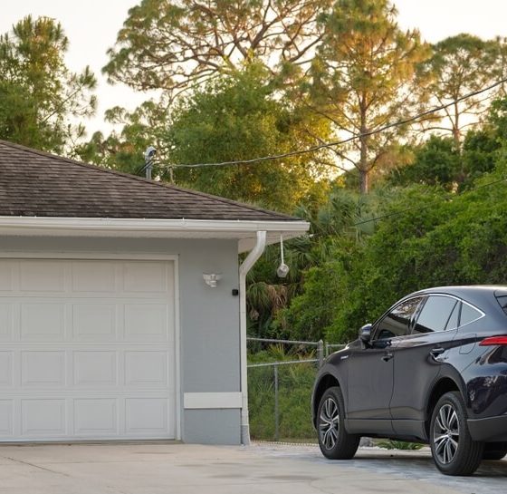 Car parked in front of wide garage double door on concrete driveway of new modern american house - Acceptance, cheap business insurance