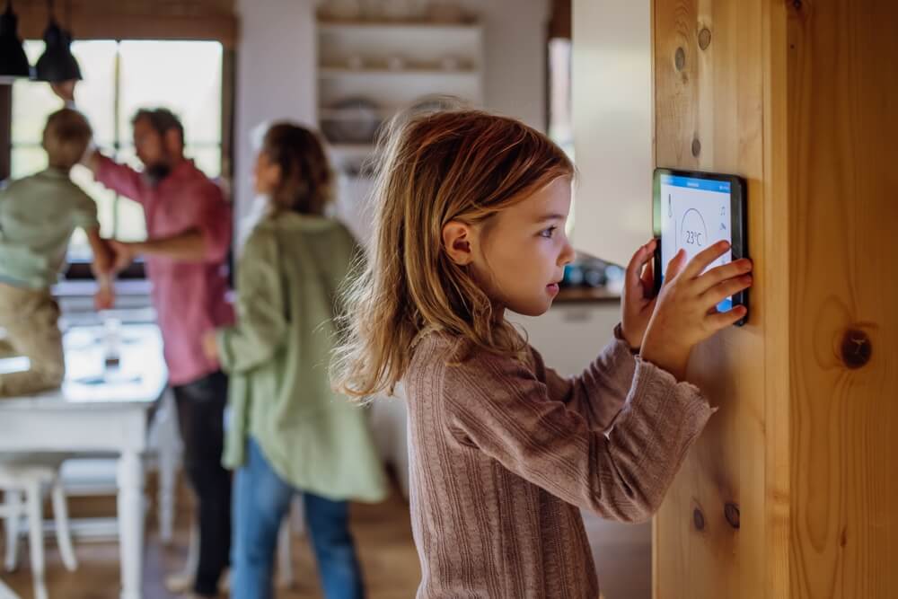 Girl looking at smart thermostat at home