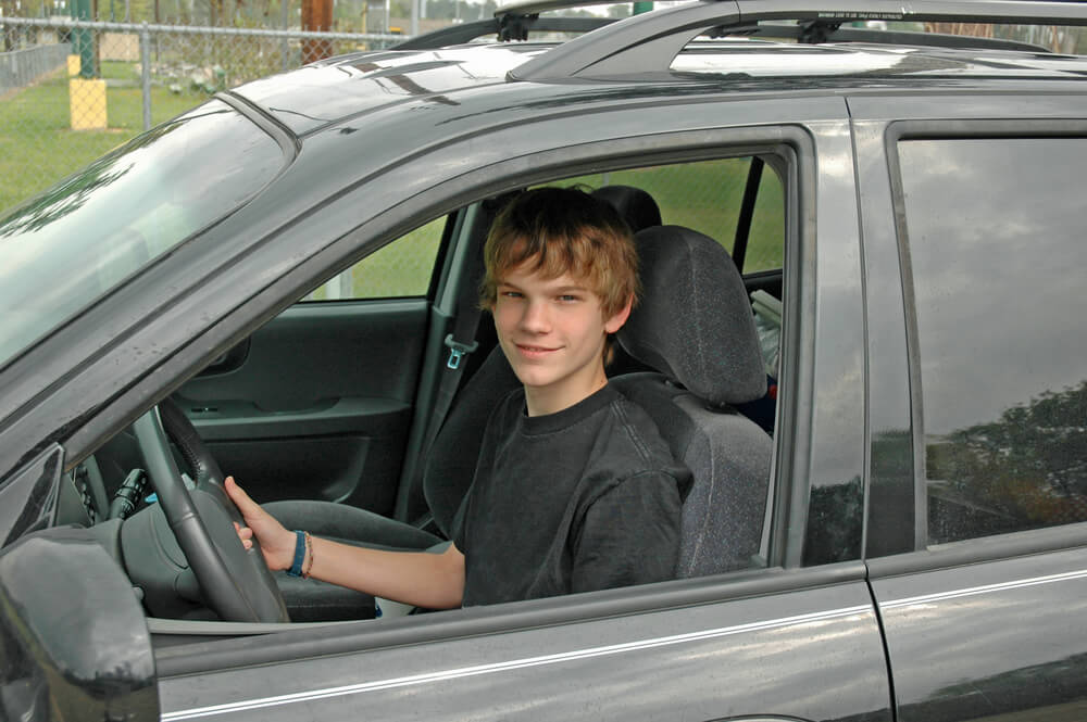 Young teenager behind the wheel of his parent's car - cheap car insurance.