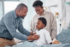 A doctor examines a little boy who is there with his mother.