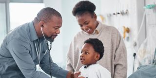 A doctor examines a little boy who is there with his mother.