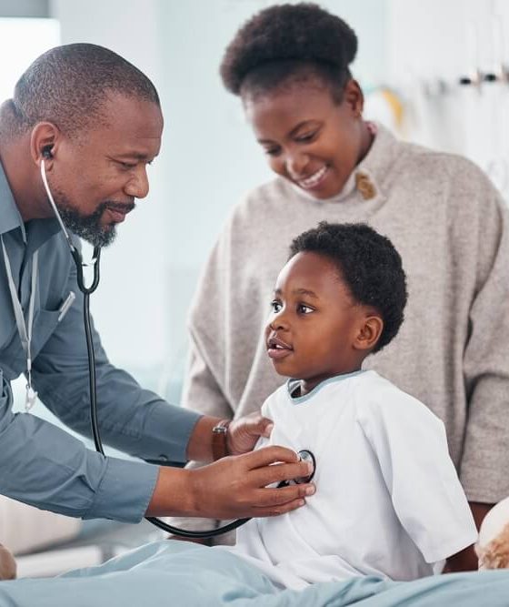 A doctor examines a little boy who is there with his mother.