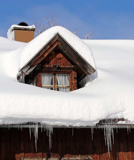 Roof of a home covered in a thick layer of snow - cheap home insurance.