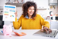 Woman buying car insurance on laptop holds her credit report in her other hand - cheap car insurance regardless of credit score.