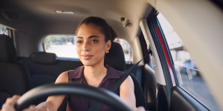 Smiling business woman driving car in city streets - Acceptance