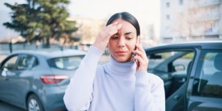 Woman on phone calling police and insurance company after a wreck - cheap car insurance.