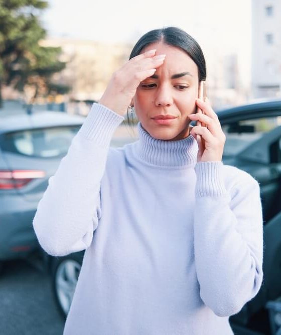 Woman on phone calling police and insurance company after a wreck - cheap car insurance.