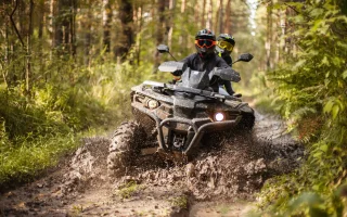 A quad moving through the mud with two riders on it – cheap ATV insurance.