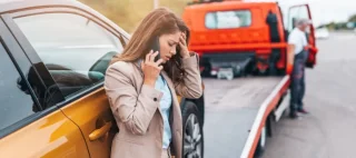 woman calling someone while roadside assistance is helping her on the road