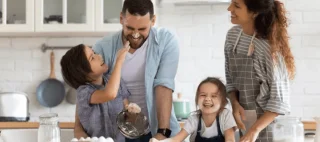 happy smiling parents enjoy weekend play with small children doing bakery cooking in kitchen