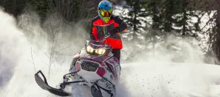 Snowmobile riding with fun in deep snow powder during backcountry tour.